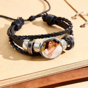 Personalized custom photo braided leather bracelet featuring a black multi-layer braided cord with an adjustable sliding knot closure and a round photo charm displaying a cherished couple's picture. A stylish keepsake bracelet for men and women, perfect as a romantic gift for anniversaries, Valentine's Day, birthdays, or special occasions.