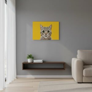 Personalized pet portrait canvas wall art featuring a gray tabby cat on a bright yellow background, displayed above a floating wooden shelf in a modern living room with a gray wall, potted plant, and beige armchair. A stylish custom pet photo print for home décor.