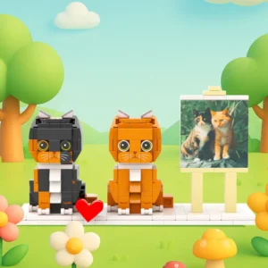 Custom brick cat figures featuring two stylized cats (black and orange) displayed on a white base, alongside a framed reference photo of two real cats on an easel. Set in a colorful outdoor-style background with trees and flowers, this personalized pet keepsake represents a custom photo-to-building-block design, ideal for cat lovers, gifts, or pet memorials.