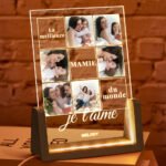 Personalized acrylic LED photo night light featuring a collage of family photos with engraved French text reading "La meilleure MAMIE du monde, je t'aime" and a custom name at the bottom. The illuminated clear acrylic panel sits on a warm LED wooden base, creating a heartfelt keepsake for grandmothers, Mother's Day, birthdays, Christmas, or family celebrations.