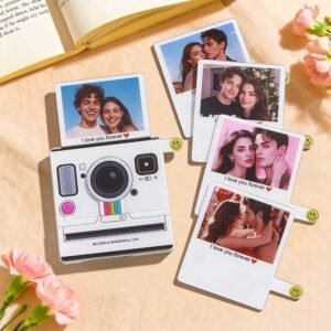 A collection of personalized photo cards styled like instant camera prints and Polaroids arranged on a tabletop. One main card is designed as a camera-shaped frame with a couple’s photo and the text “I love you forever,” while other photo cards show romantic couple portraits with similar captions. The layout suggests customizable love-themed photo gifts for couples.