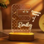 Personalized acrylic initial jewelry holder shaped like the letter “E,” featuring a custom name “Emily,” warm LED lighting, and a wooden base. The clear earring organizer includes multiple holes for storing earrings and small jewelry pieces, making it a decorative personalized gift for bedrooms, dressing tables, birthdays, bridesmaids, Mother’s Day, or jewelry lovers.