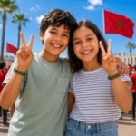 Two smiling children wearing Morocco-themed silicone wristbands posing outdoors, with a Moroccan flag in the background, both showing peace signs in a festive football fan atmosphere.