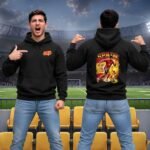 Spain football hoodie - printshop4me.ae "Front and back view of black Spain football hoodie featuring Yamal soccer player illustration, Spain national team colors, dynamic action pose, modeled in stadium seating."