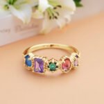 Elegant gold birthstone ring featuring five colorful gemstones in mixed shapes and sizes, including blue, purple, green, pink, and lavender stones in a vintage-inspired setting. This personalized family birthstone ring symbolizes loved ones and makes a meaningful gift for mothers, wives, grandmothers, birthdays, anniversaries, Mother's Day, and special occasions.