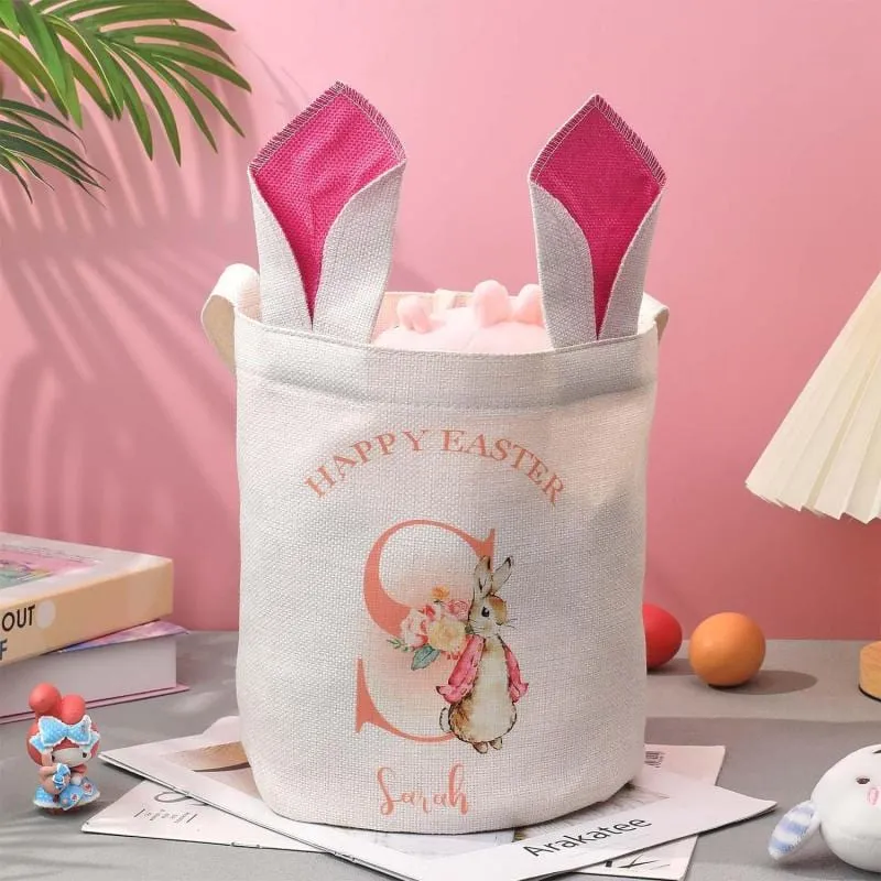 e513ccf9bebf16e4c53d880386e00f5bwebp - printshop4me.ae Personalized Easter bunny gift basket featuring a white fabric tote with bunny ear design, rabbit illustration, and custom name print. A festive Easter storage bag for holding eggs, candies, and small gifts, suitable for spring celebrations and holiday gifting.