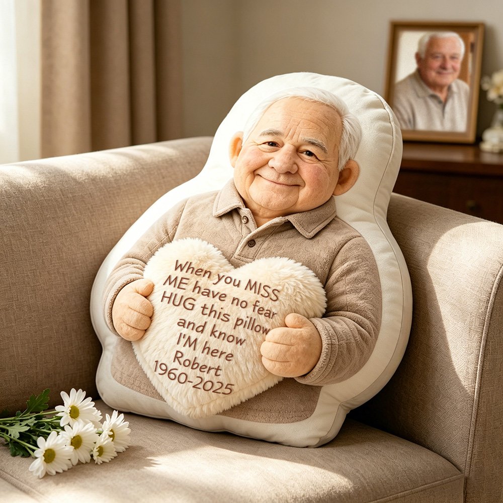ef4b98d7-24c9-4311-8b34-b9d26bf7619c-0jpeg - printshop4me.ae Personalized memorial photo pillow featuring a cartoon-style elderly man holding a heart cushion with a heartfelt message, displayed on a sofa in a cozy living room setting.