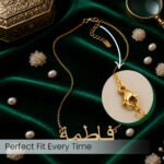 Gold necklace with Arabic script pendant laid on green velvet; close-up shows the lobster-claw clasp.