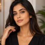 Close-up portrait of a woman with long dark hair wearing a gold Arabic-script necklace and a black top.