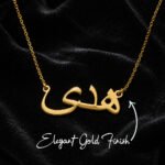 Gold name pendant with Arabic script on a black velvet background, hanging from a delicate chain